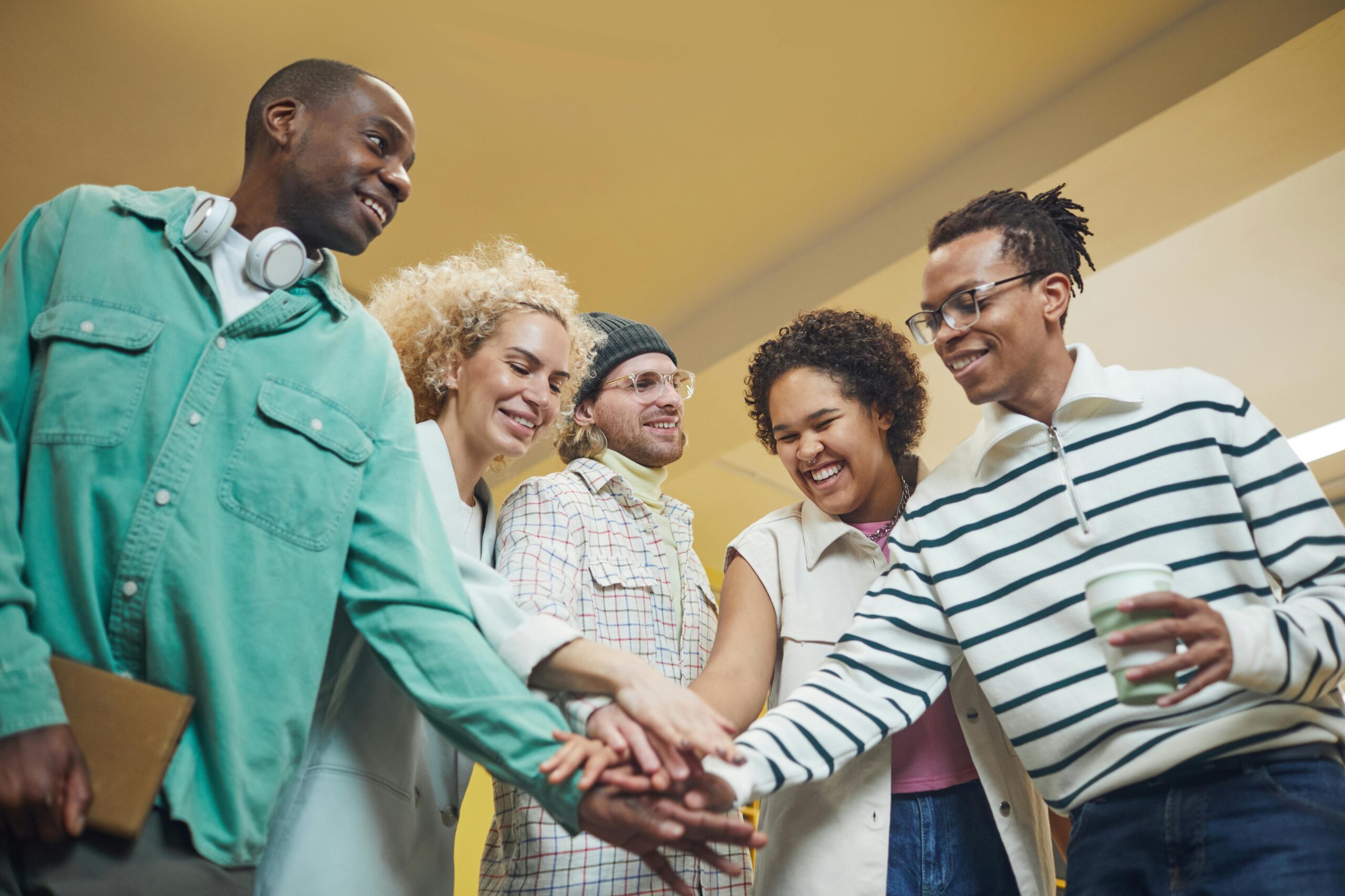 Colleagues standing together together and stacking hands, embodying a strong team culture.